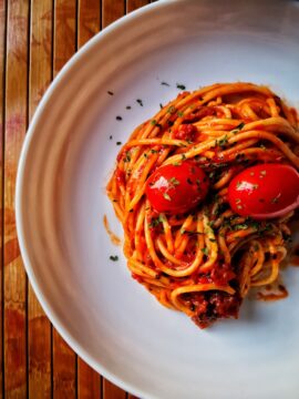 Strona główna a white plate topped with spaghetti and tomatoes